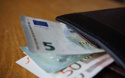 Das Foto zeigt eine schwarze Gedlbörse mit verschiedenen Euro-Banknoten darin, die auf einem Holztisch liegt. Quelle: martinprague/stock.adobe.com 