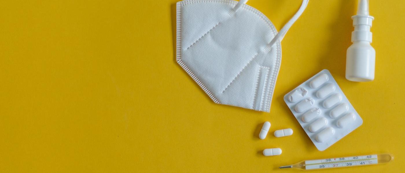 On a yellow background are a white FFP2 mask, a white nasal spray, a glass clinical thermometer and a tablet blister, three tablets of which are already lying individually next to the blister. Image source: Elizaveta/stock.adobe.com On a yellow background are a white FFP2 mask, a white nasal spray, a glass clinical thermometer and a tablet blister, three tablets of which are already lying individually next to the blister. Image source: Elizaveta/stock.adobe.com