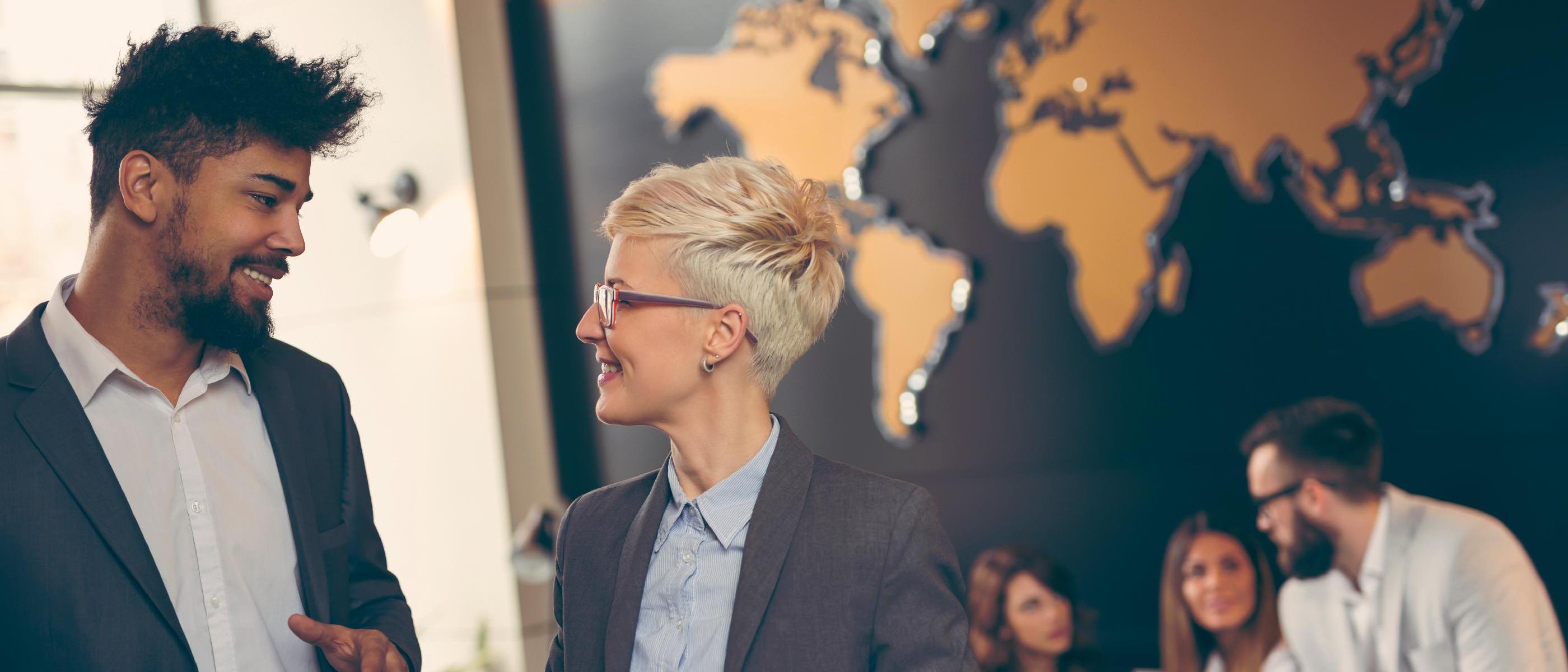 Two people are talking. There is a map of the world in the background.. Source: Impact Photography/stock.adobe.com Two people are talking. There is a map of the world in the background.. Source: Impact Photography/stock.adobe.com
